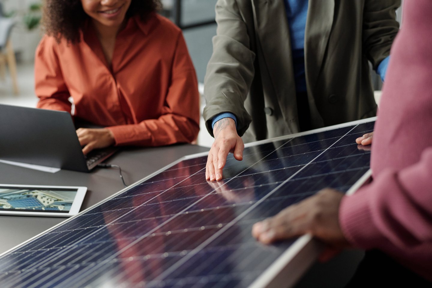 Overleg over zonnepanelen met een zonnepaneel en een laptop op tafel