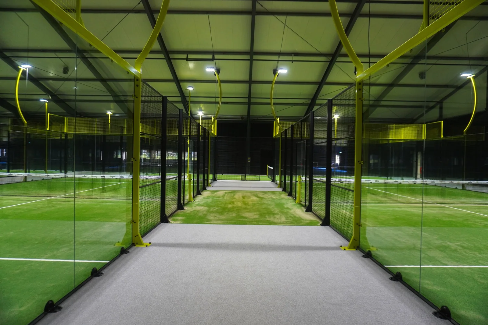 Groene indoor padelbanen van Padelclub Hem met gele staanders en baanverlichting